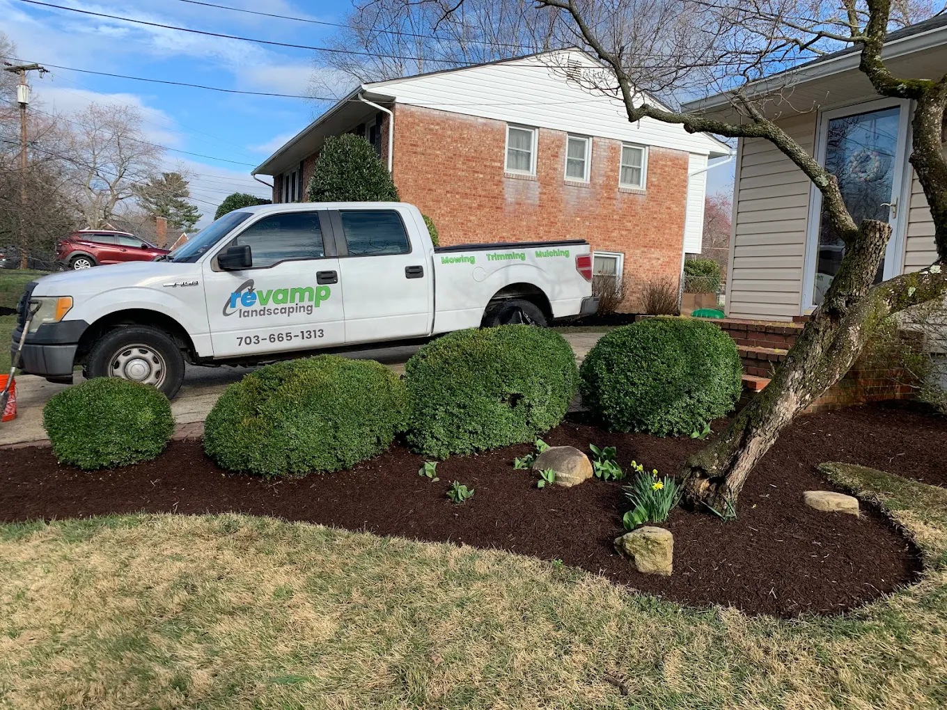 Revamp Landscaping truck parked next to neatly trimmed bushes and mulched garden