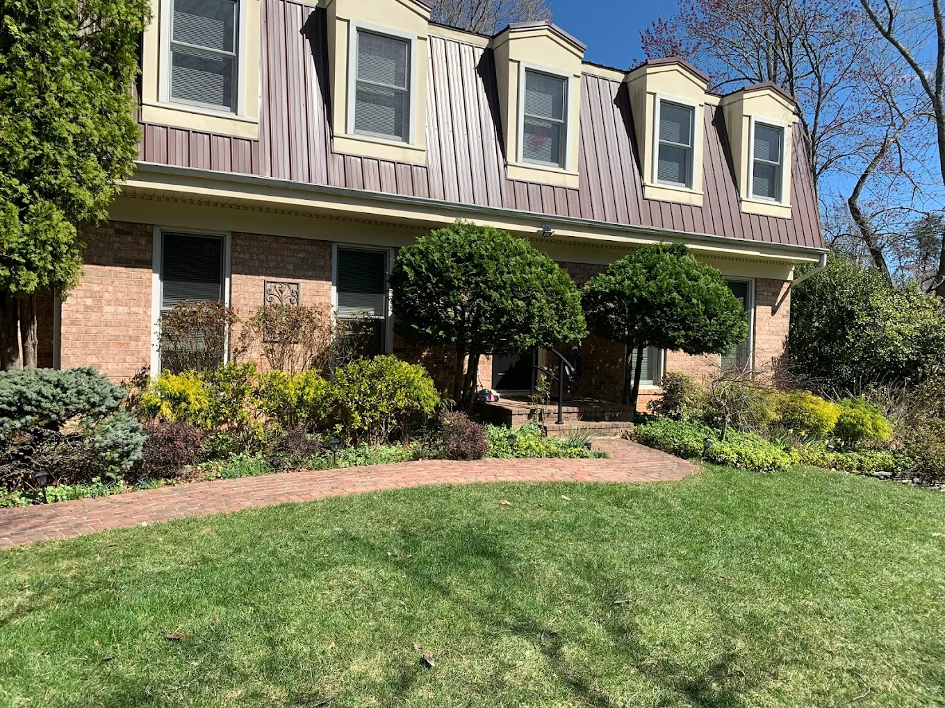 Brick two-story house with manicured landscaping and green lawn
