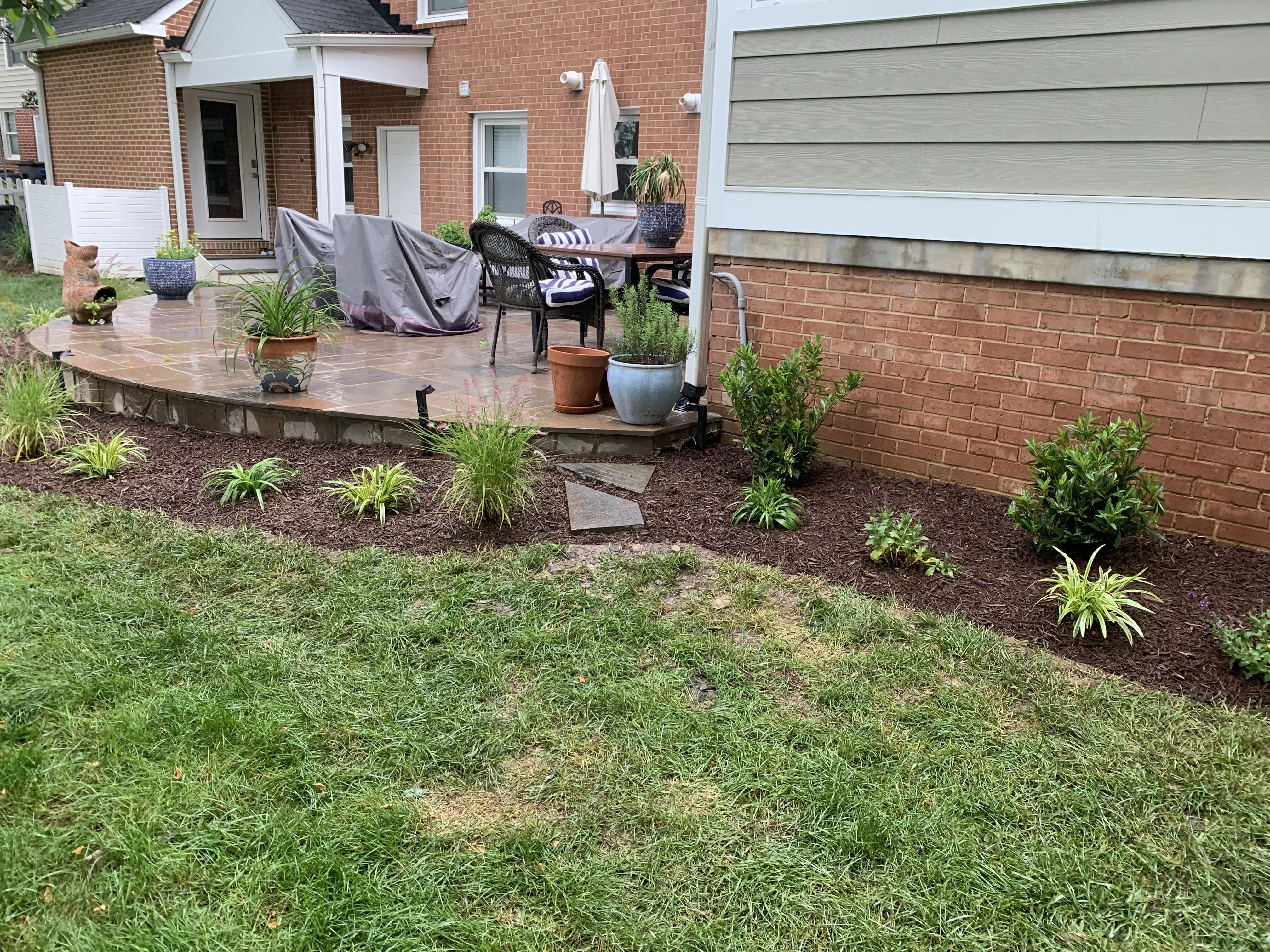 Backyard patio with stone tiles, potted plants, and outdoor furniture